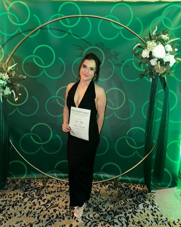 Jenny in a black dress holding her Finalist 2025 certificate at the awards night